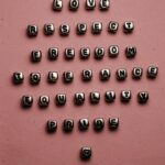 Letter beads forming inspiring words on a pink surface, promoting love, respect, and equality.